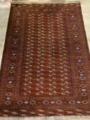 A hand knotted bokhara rug, the red field with four rows of guls framed within a multi line