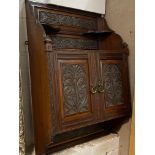 An Edwardian mahogany wall hanging cabinet, with open shelves over twin doors with floral carved