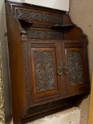 An Edwardian mahogany wall hanging cabinet, with open shelves over twin doors with floral carved