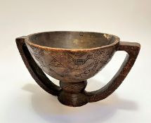 An African carved circular meal bowl with relief carved bird and circular design with twin handles