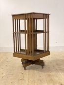 An Edwardian oak revolving bookcase with two tiers, on a cruciform base moving on castors, H87cm,