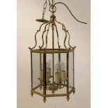 A gilt brass hall lantern of hexagonal outline, with inset glass panels enclosing six branches,