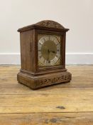 An Edwardian oak cased mantle time piece clock, the domed top over floral scroll carved frieze and