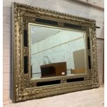 An ornate silver gilt wall hanging mirror with bevelled plate, 130cm x 101cm