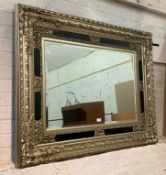 An ornate silver gilt wall hanging mirror with bevelled plate, 130cm x 101cm