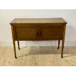 An Edwardian oak side cabinet, with two inlaid drawers, raised on square tapered supports with