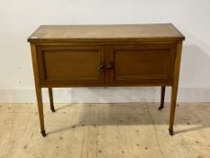 An Edwardian oak side cabinet, with two inlaid drawers, raised on square tapered supports with