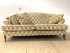 A large traditional sofa, upholstered in gold coloured cut velvet with a repeating floral design,