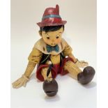 A fibreglass moulded figure of seated Pinocchio decorated with polychrome enamels, missing Jimney