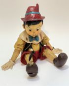 A fibreglass moulded figure of seated Pinocchio decorated with polychrome enamels, missing Jimney