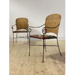 A pair of vintage wrought iron and rattan chairs, with scrolled open arms and upholstered seats