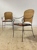 A pair of vintage wrought iron and rattan chairs, with scrolled open arms and upholstered seats