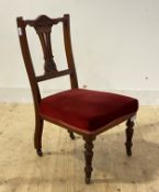 A late victorian walnut salon chair with upholstered seat, raised on turned supports and castors,