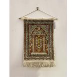 A Persian design silk wall hanging, the field with mihrab enclosed by a multi line border 57cm x