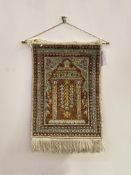 A Persian design silk wall hanging, the field with mihrab enclosed by a multi line border 57cm x