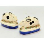 A pair of Staffordshire style seated rabbit pottery figures raised on oval floral mounted bases