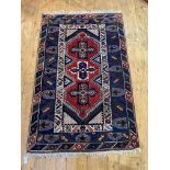 A Turkish hand knotted rug, the red field with triple medallion and bordered 124cm x 203cm