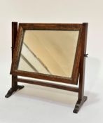 A 19thc mahogany swing mirror, the rectangular mirror with relief carved slip, raised on tapered end