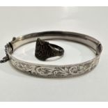 An Edwardian silver engraved stiff hinged bangle complete with safety chain, (d 7cm) with crest,