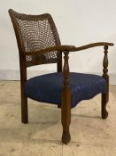 A 1930s stained beech bedroom chair, the cane back with carved motif over seat upholstered in