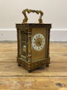 A Late 19th/ early 20th century gilt brass carriage clock, the four glass case with swing handle