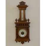 A late 19th century oak wall hanging aneroid barometer and thermometer with ivorine registers H54cm