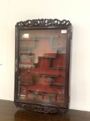 A Chinese style hardwood wall hanging display cabinet, with fret work surmount and apron and a