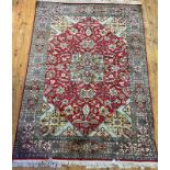 A Persian design silk pile rug, the red field with star medallion enclosed by interlaced trailing