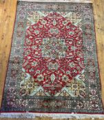 A Persian design silk pile rug, the red field with star medallion enclosed by interlaced trailing