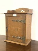 An Edwardian walnut smokers cabinet, the raised shaped top over door with strap hinges, (one hinge