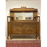An impressive and large Arts and Crafts oak buffet, the raised broken arched back having a marquetry