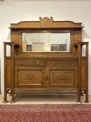 An impressive and large Arts and Crafts oak buffet, the raised broken arched back having a marquetry