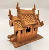 A Thai hardwood miniature temple with pitched roof and pierced windows to side, raised on