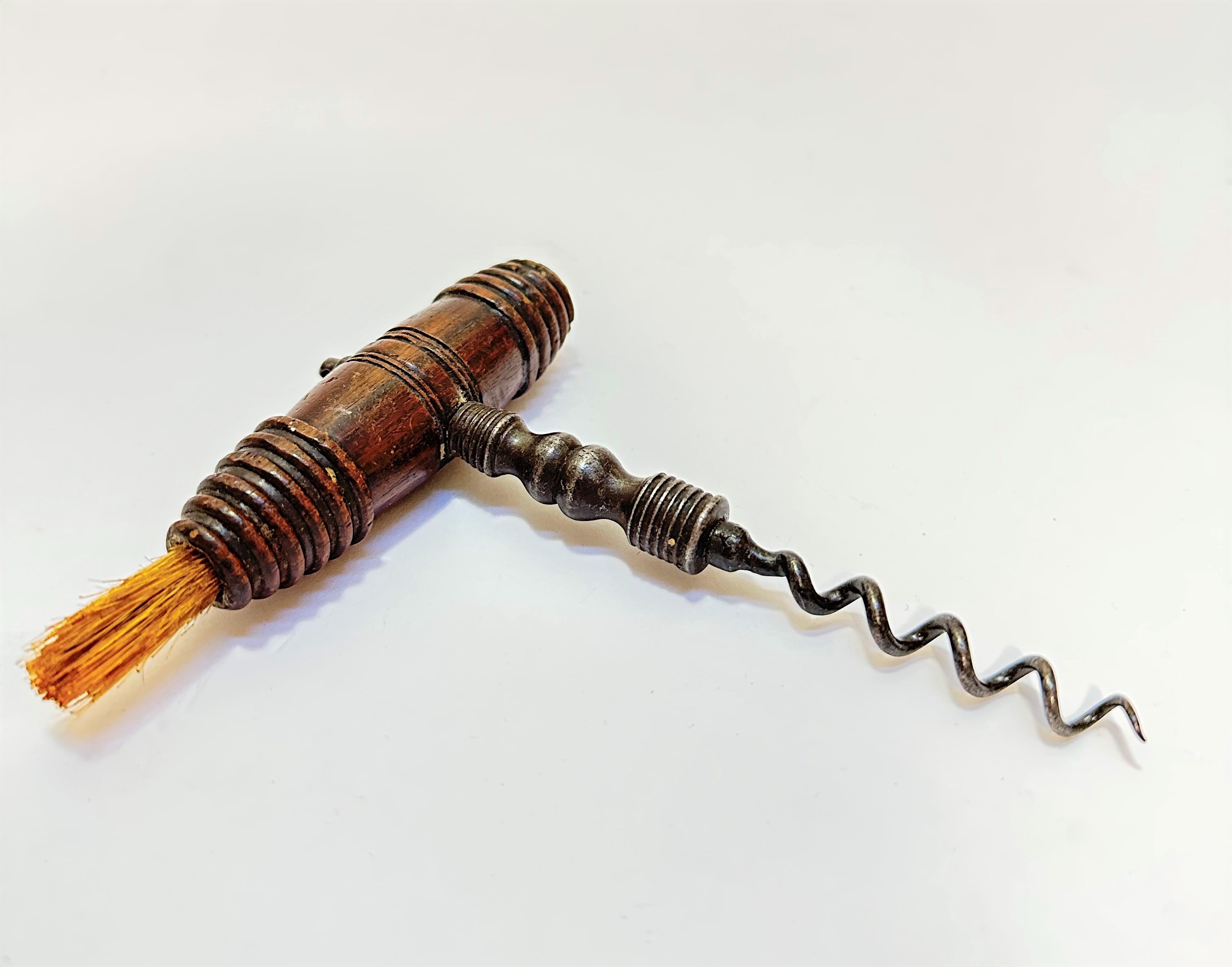 A 19thc mahogany handled cork screw with bristle end, of turned barrel form with steel corkscrew, (