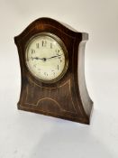 An Edwardian mahogany arched mantel clock with box wood strung and inlaid front with enamelled