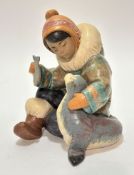 A Lladro porcelain Eskimo figure of a young girl feeding a seal pup, decorated with polychrome
