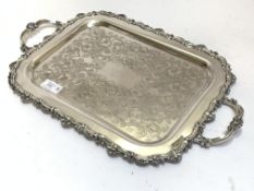 A silver plated twin handled drinks tray of Georgian design, the edge with conforming scrolls and