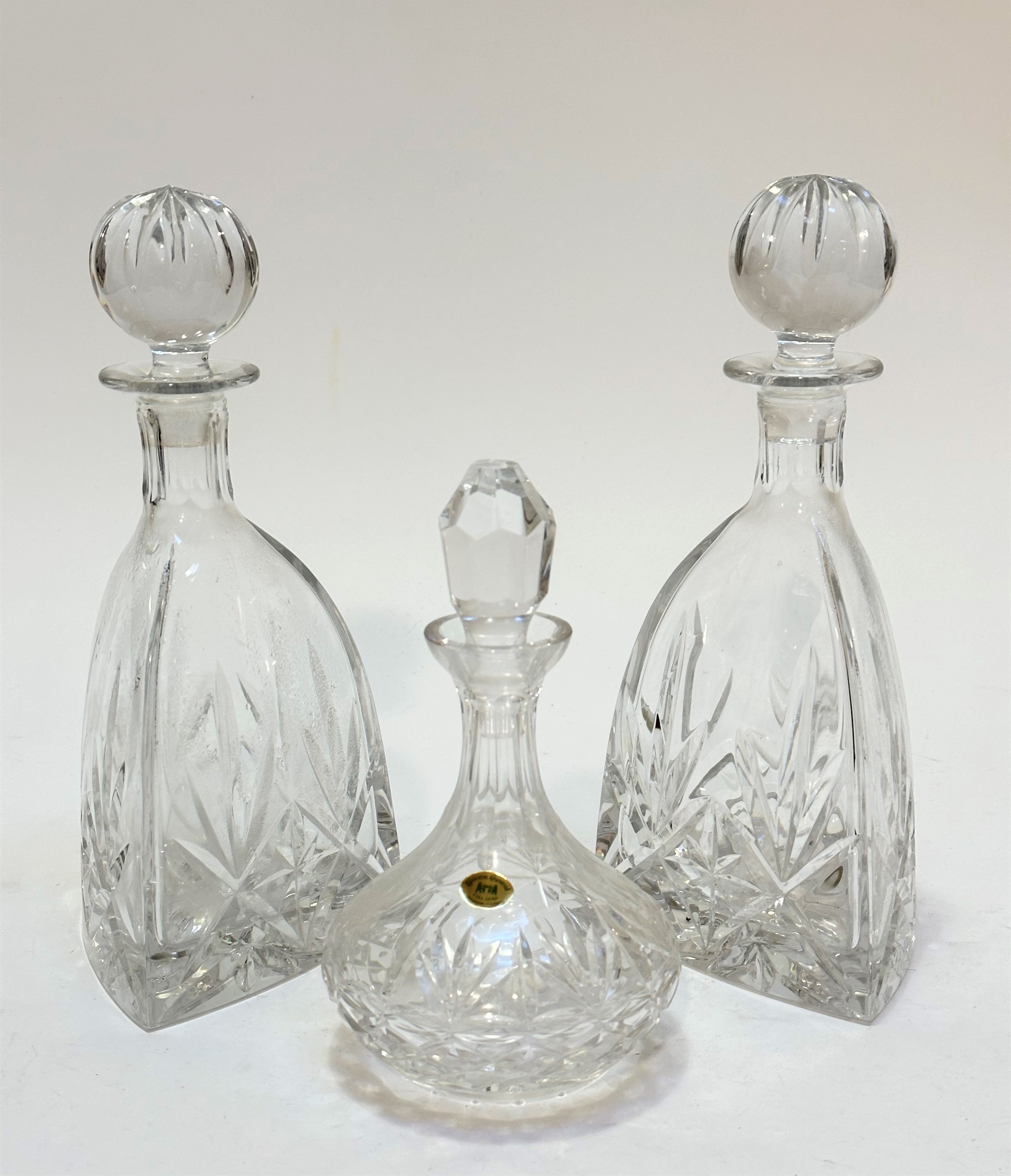 A pair of crystal slice cut triangular shaped decanters complete with ball stoppers, show no signs