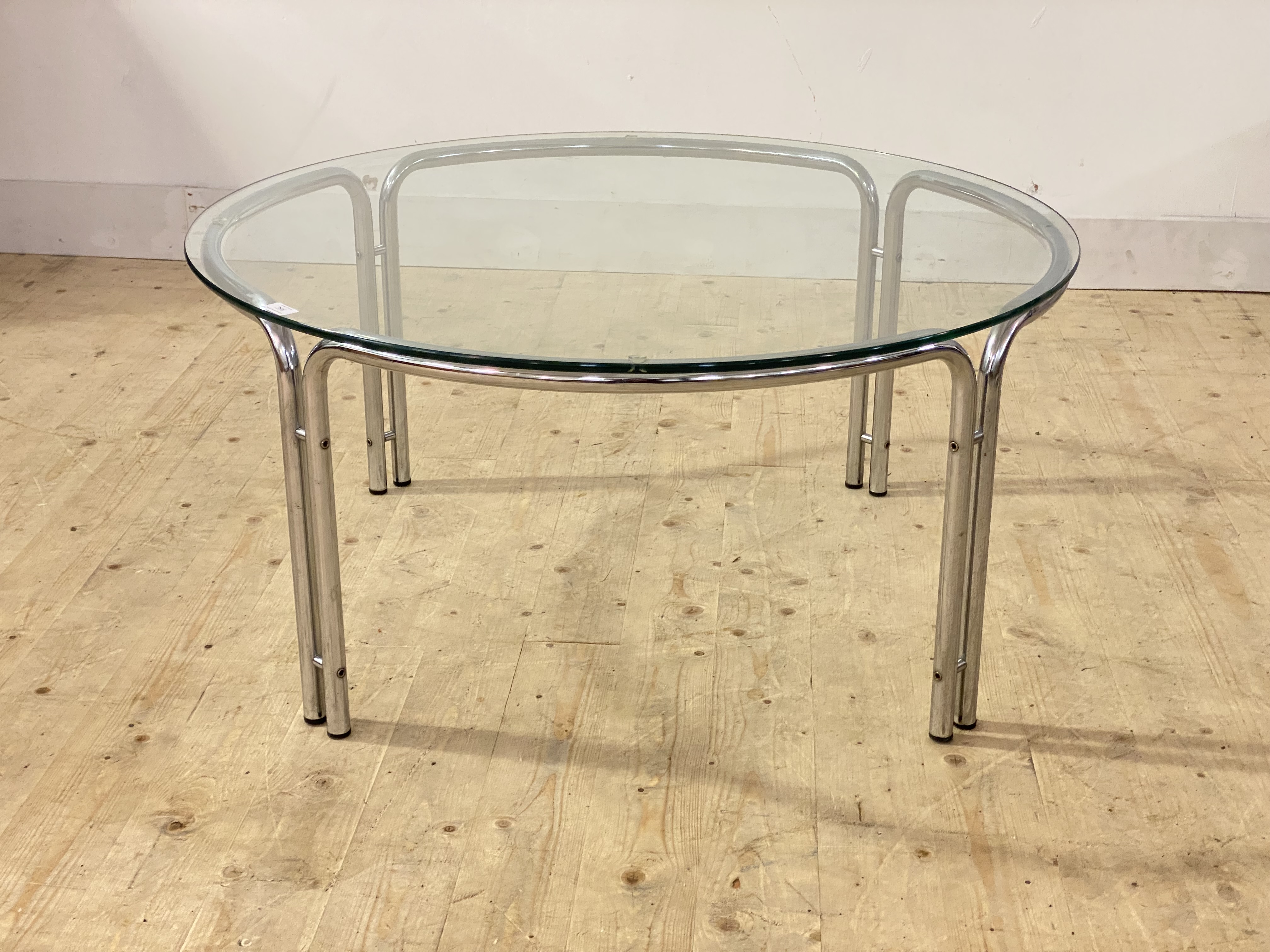 A post modern coffee table, the circular glass top raised on chromium plated tubular supports,