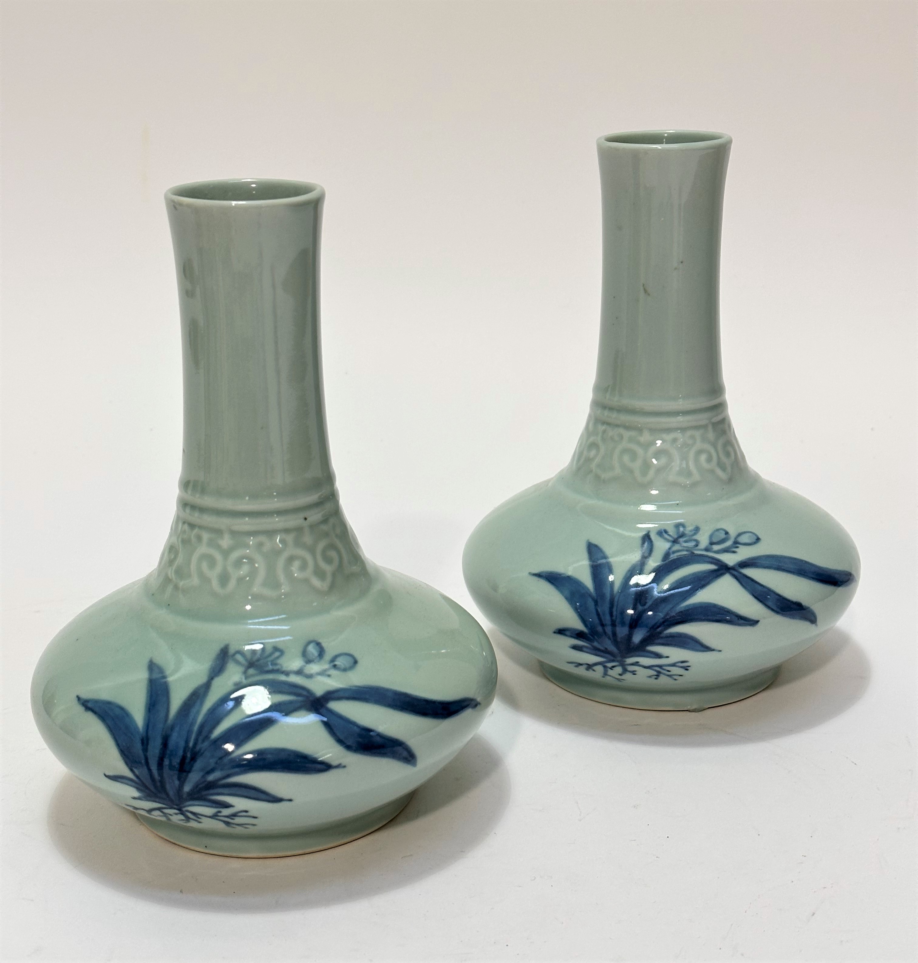 A pair of modern slim necked onion shaped celadon ware vases decorated with stylised lotus leaf