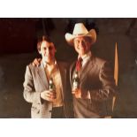 A photograph of Larry Hagman aka JR Ewing, posing with Marketing Gentleman with Bottles of Heineken,