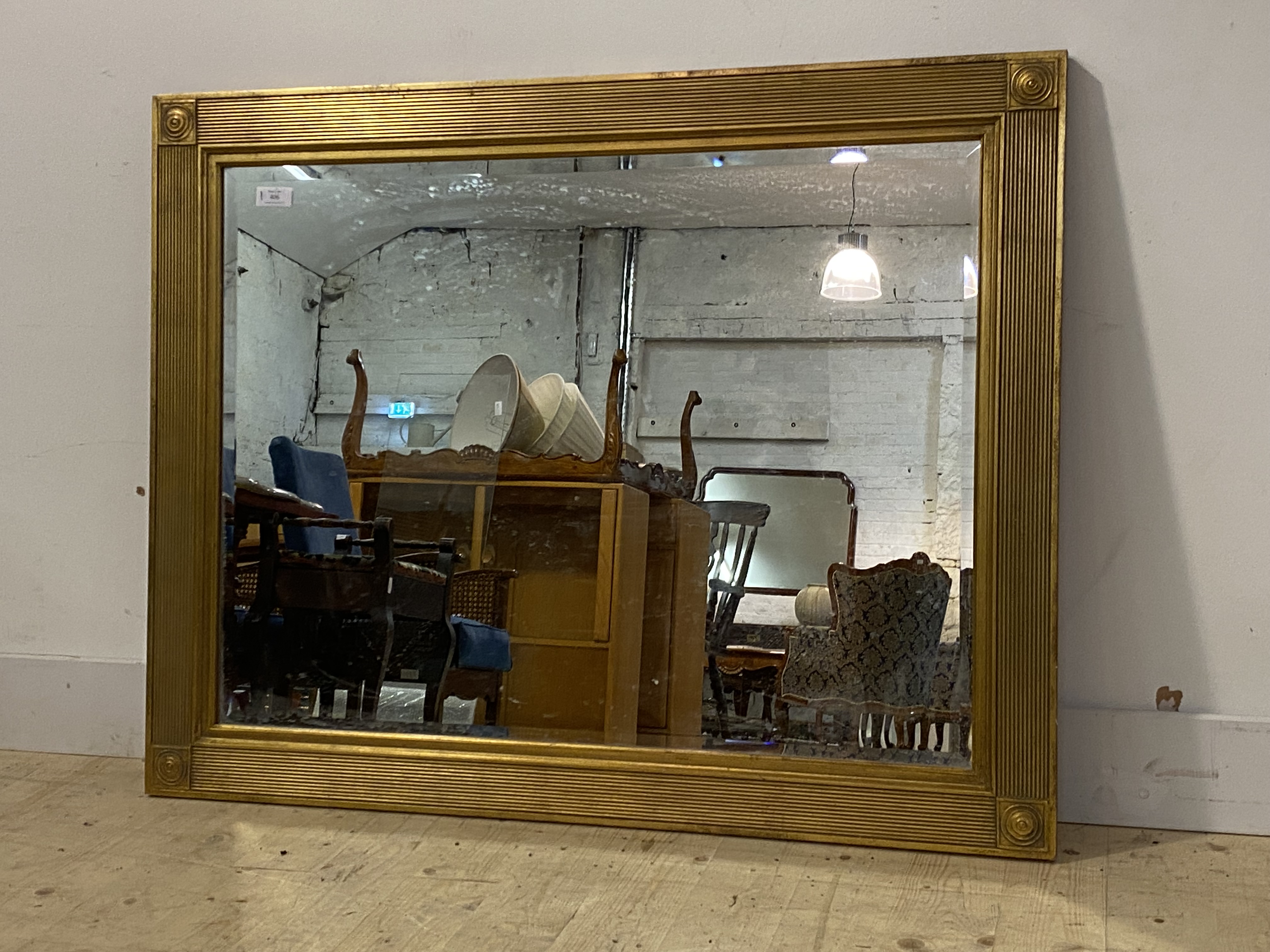 A gilt framed wall hanging mirror, reeded frame with bullseye to each corner enclosing a bevelled