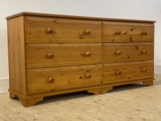 A polished pine six drawer chest raised on bracket supports, H72cm, W150cm D46cm