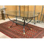 A Paniated metal dining table, the oval glass top over corners with gilt metal cast lion masks,