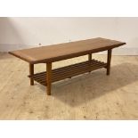A mid century teak coffee table, with chamfered edge to top over slatted magazine rack, raised on