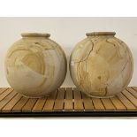 A pair of contemporary travertine or polished sandstone vases of spherical form with flared rims,