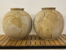 A pair of contemporary travertine or polished sandstone vases of spherical form with flared rims,