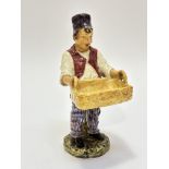 A 19thc continental pottery figure of a boy with bread basket raised on circular moulded base,