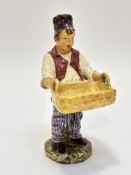 A 19thc continental pottery figure of a boy with bread basket raised on circular moulded base,