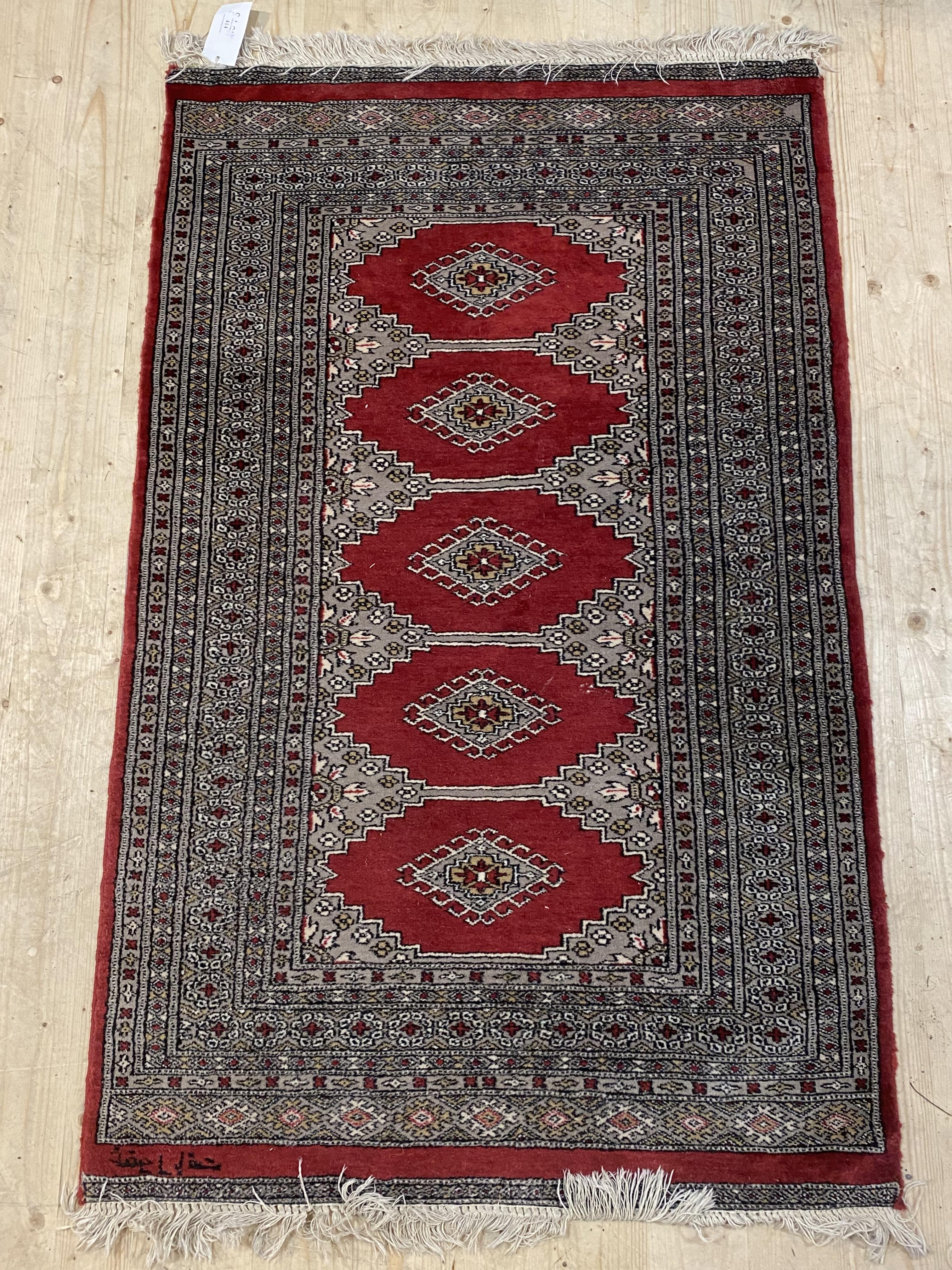 An Afghani bokhara rug, hand knotted and signed to border 95cm x 160cm